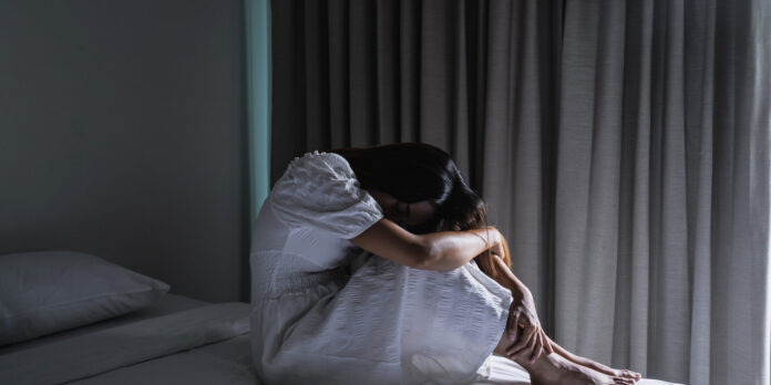 Lonely young woman feeling depressed and stressed sitting in the dark bedroom, Negative emotion and mental health concept